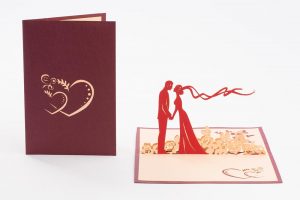 Pop up Wedding Card: Bride and groom holding handa about to kiss, standing in flowers wind blowing (cover and inside)