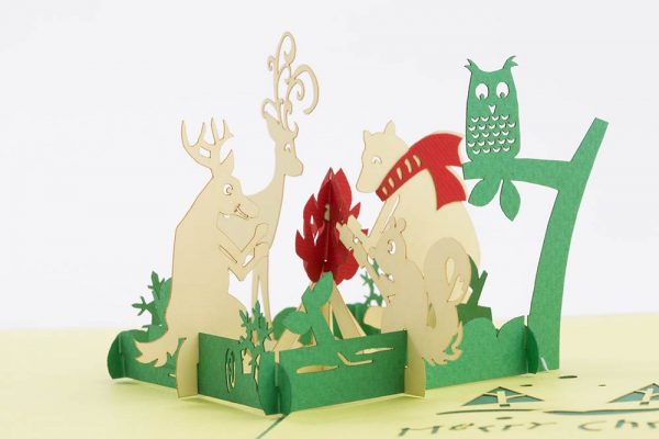 3D pop up greeting cards , a 3D Christmas scene with a reindeer, bear, owl, squirrel, deer sitting around a campfire.Close up