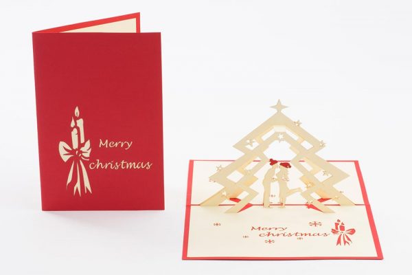 Christmas pop up greeting cards: A 3D pop up scene with a couple kissing under a Christmas tree .