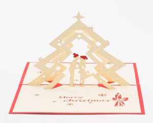 Christmas pop up greeting cards: A 3D pop up scene with a couple kissing under a Christmas tree .