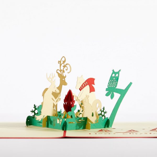 Christmas 3D pop up greeting card: A 3D Christmas scene with a reindeer, whit tailed deer, owl and squirrel sitting around a campfire.