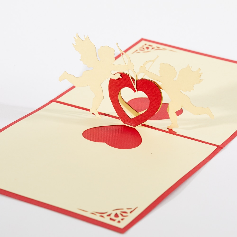Valentines 3D pop up card: Two cupids stretched over a heart touching bows together.